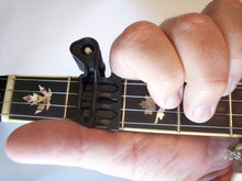 Load image into Gallery viewer, It stays out of way of your hand movements.  - It capos the string right at the fret, not between the frets, Your can actually slide BEHIND the capo, as when you&#39;re playing a &quot;C&quot; chord, as shown.
